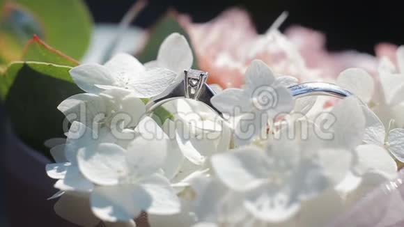 一束白花上的结婚戒指婚戒和白色和粉色花束的旋转组合视频的预览图