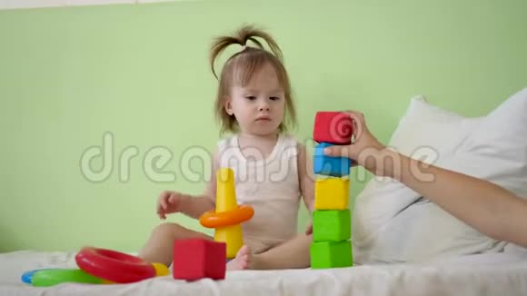 孩子和妈妈在床上玩五颜六色的立方体学前和幼儿园儿童的教育玩具儿童玩具视频的预览图