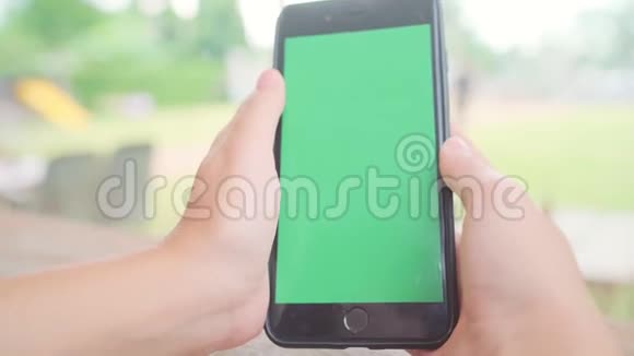 年轻的亚洲女性使用带有绿色屏幕的黑色手机设备亚洲女人拿着智能手机在咖啡馆里滚动页面视频的预览图