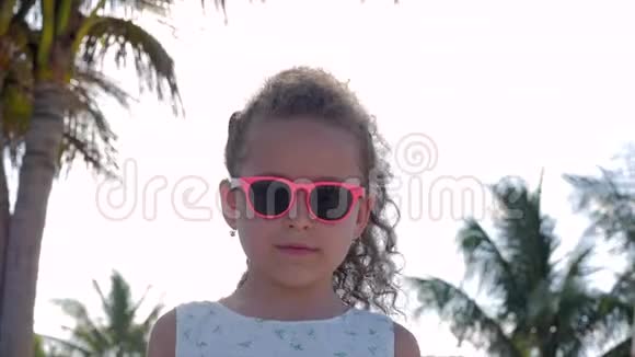 特写肖像一个漂亮的小女孩戴着粉红色的眼镜可爱的微笑着看着镜头概念儿童视频的预览图