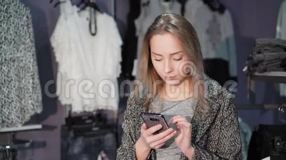 在服装店里用手机的漂亮女孩4K视频的预览图