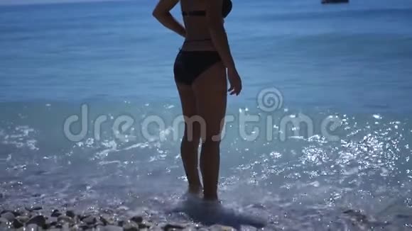 一个穿着泳衣的苗条女孩站在水里海浪拍打着她的腿高清1920x1080慢慢慢慢视频的预览图
