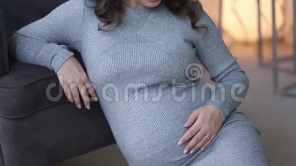 孕妇坐在扶手椅附近有灯光的床背景美丽的女人在家里度过时光视频的预览图