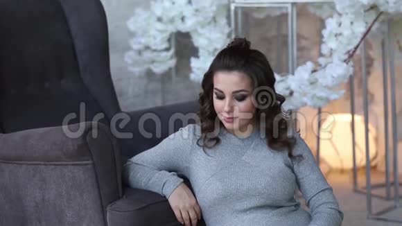孕妇坐在扶手椅附近有灯光的床背景美丽的女人在家里度过时光视频的预览图
