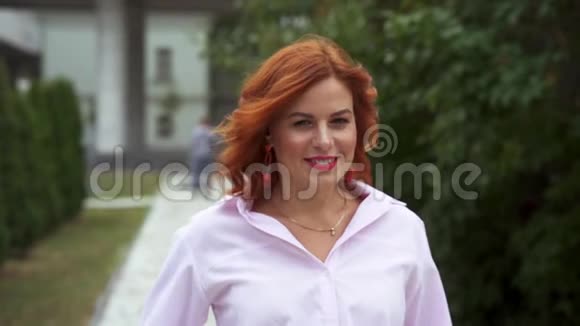 一个红头发的漂亮女人的肖像那个女人慢慢地沿着公园的小路走视频的预览图