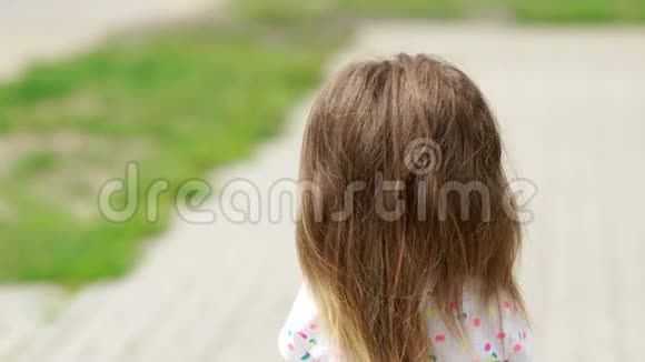美丽的小女孩转过身来看着镜头布鲁内特长发浓密的头发鲜花的气息视频的预览图