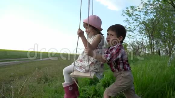 孩子们在荡秋千两个孩子骑着慢动作兄弟姐妹一起荡秋千小女孩和男孩在旋转视频的预览图