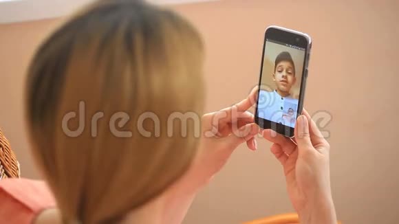 一个女人带着孩子在智能手机上做视频游戏视频的预览图