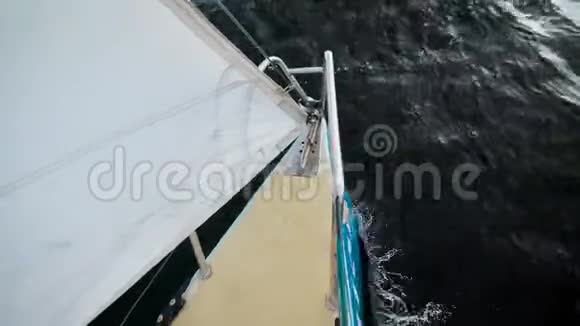 白色帆小帆船的鼻子白天坐着暗波的大海从顶部可以看到视频的预览图