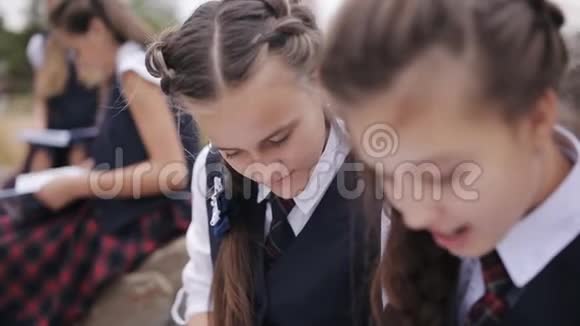 一群年轻的朋友穿着相同的校服坐在户外聊天读一本书视频的预览图