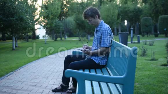 苗条的男人坐在长凳上写着记事本视频的预览图