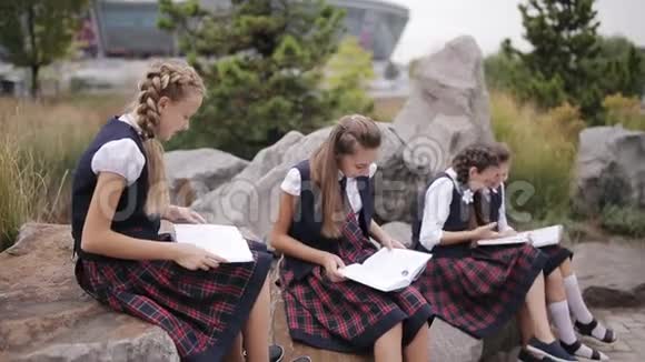一群年轻的朋友穿着相同的校服坐在户外聊天读一本书视频的预览图