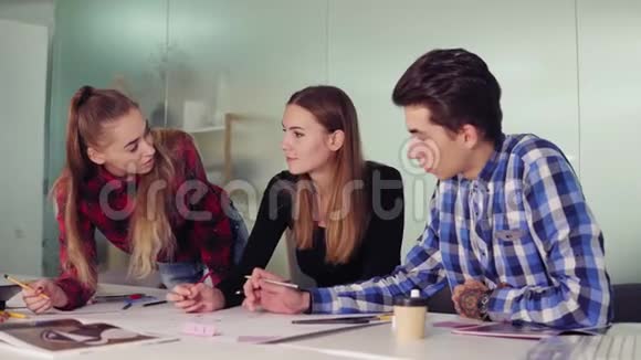 由三人组成的创意商业团队在一个现代化的办公室开会边坐边讨论商业想法视频的预览图