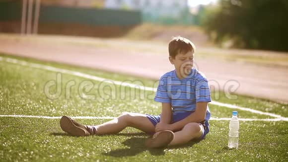 小男孩足球运动员在训练期间从塑料瓶里喝水青少年踢足球视频的预览图