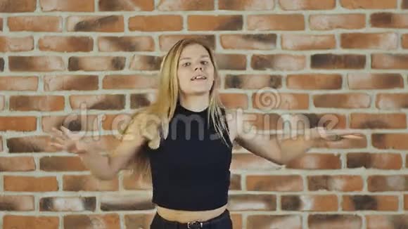 嘻哈金发女孩在城市砖墙上以现代风格跳舞慢动作视频的预览图