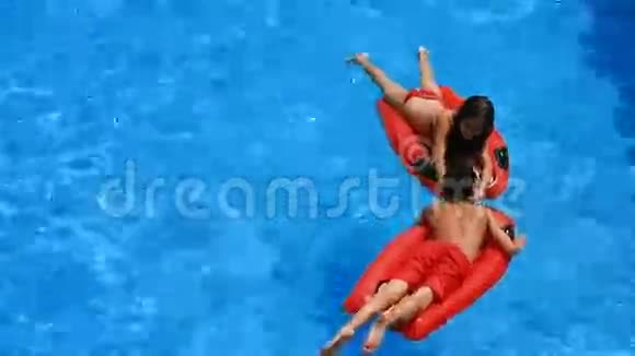 孩子们一个男孩和一个女孩漂浮在游泳池里的充气床垫上从上面看视频的预览图