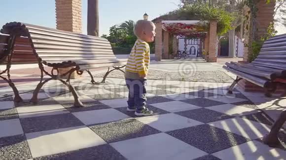 阳光明媚的夏天stadicam拍摄的小男孩在人行道上奔跑慢动作视频的预览图