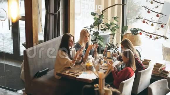 四个美女坐在咖啡馆里打电话视频的预览图