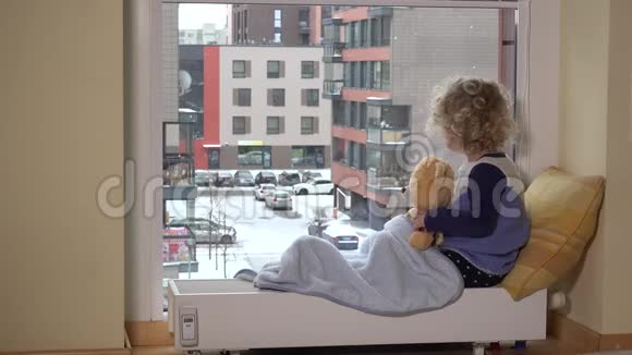 女孩和最好的朋友泰迪熊看着窗外的大雪视频的预览图