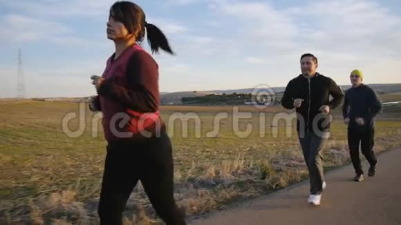 与户外私人教练一起健身秋天或春天两个男人和女人在乡间的道路上缓慢地奔跑视频的预览图