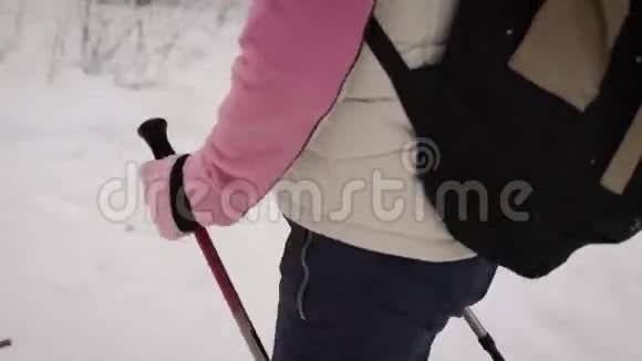 一个精力充沛的女人在森林里快步走着形象的焦点是女士的手挂着黑色的滑雪杆视频的预览图