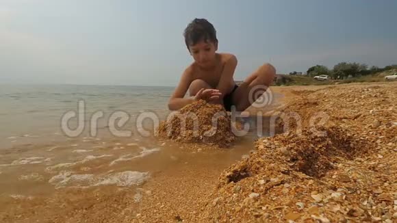 男孩在沙滩上玩沙前景视频的预览图