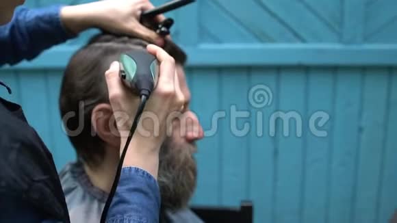 理发师用电动剃须刀和梳子剪客户的头发视频的预览图