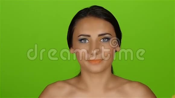 女孩有一个美丽明亮的化妆覆盖眼睛一半的橘子绿色屏幕慢动作视频的预览图