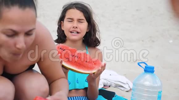 孩子们青少年在海滩上休息笑着吃西瓜慢动作视频女孩少年休息视频的预览图