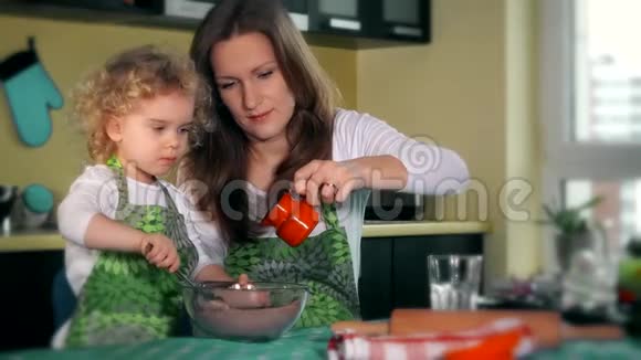漂亮的妈妈教女儿在厨房准备面团家庭幸福视频的预览图