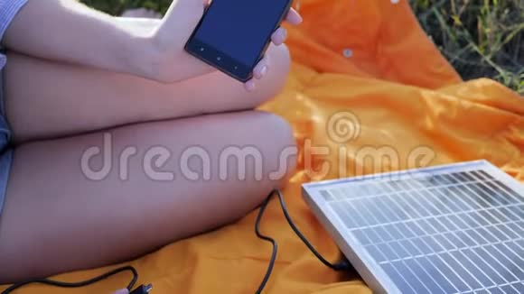 关闭屏幕蜂窝电话手女孩连接从太阳能电池板到手机外面年轻女子收费视频的预览图