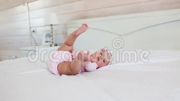 穿着粉红色衣服的漂亮婴儿躺在家里的床上视频的预览图