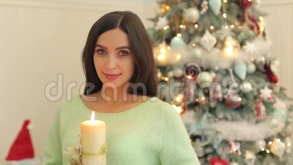 手里拿着蜡烛靠近圣诞树的女孩视频的预览图