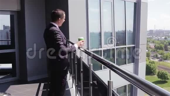 商人带着一杯咖啡去商务中心的阳台视频的预览图