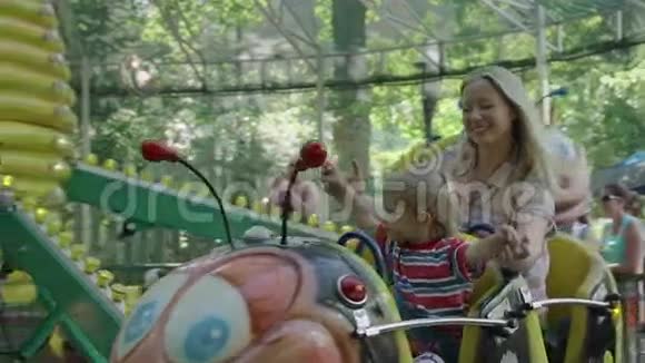 妈妈和她的小男孩正在游乐园骑毛毛虫视频的预览图