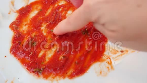 用番茄酱的残留物清空脏盘子男人手在番茄酱的残骸上画一颗心4k慢镜头视频的预览图