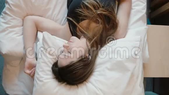 刚起床的年轻女人早上醒来微笑着黑发长发女孩下床视频的预览图