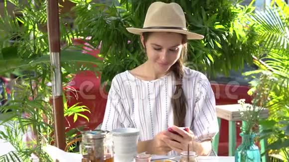 女人一边喝茶一边在智能手机上写信息视频的预览图