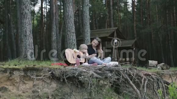 小金发女孩弹吉他和母亲坐在悬崖上视频的预览图