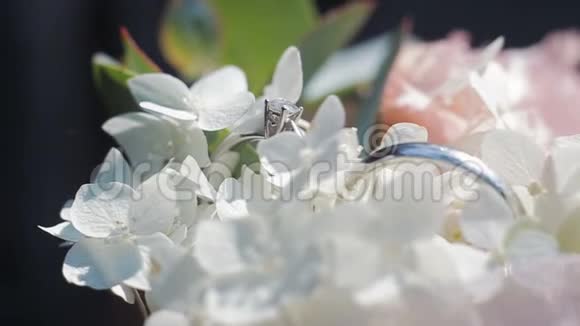 一束白花上的结婚戒指婚戒和白色和粉色花束的旋转组合视频的预览图