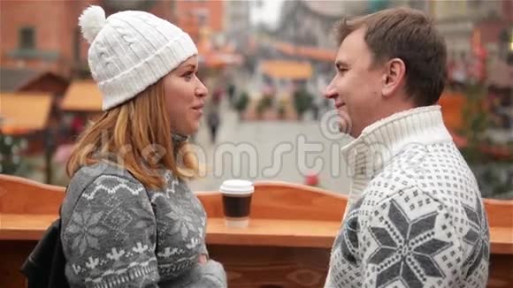 英俊的男人和美丽的女人面对面站在咖啡杯在圣诞节市场背景恋爱中的情侣视频的预览图