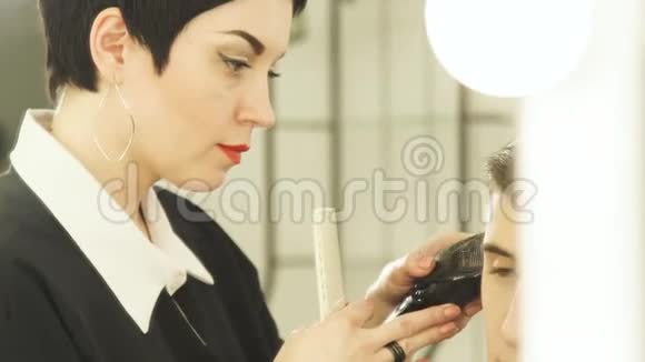 女人用电动剃须刀做男性发型在理发店里用剪发器把理发师的头发剪好男子视频的预览图