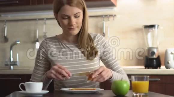 漂亮的年轻人用果酱做面包和黄油厨房里有果汁和咖啡的早餐视频的预览图