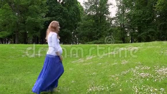 阳光明媚的夏日怀孕的女性穿过公园草地视频的预览图