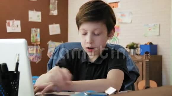 可爱的小男孩在他的房间里为学校写论文做作业视频的预览图