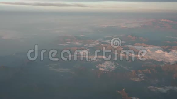 日出时飞越阿尔卑斯山从飞机窗口可以看到空中景色视频的预览图