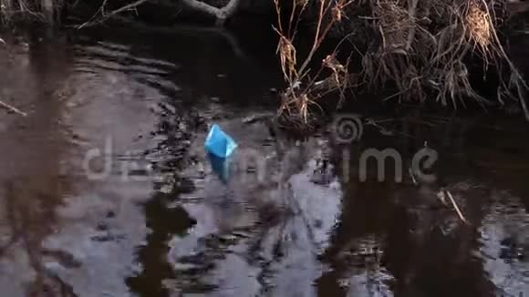 彩纸蓝纸船沿河岸漂浮视频的预览图