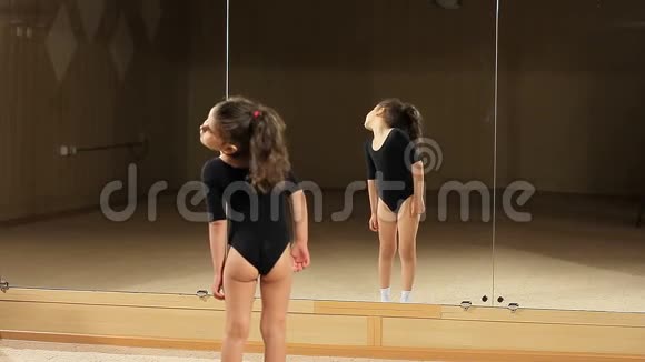 教一个体操小女孩小女孩在训练前热身镜前训练视频的预览图