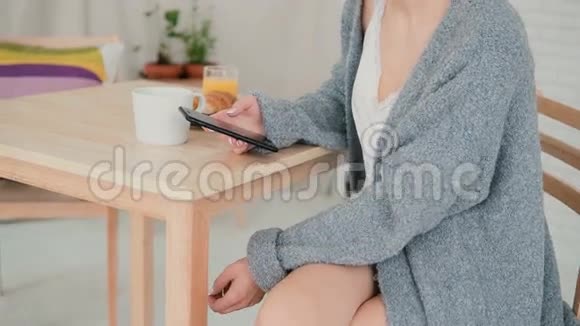使用智能手机在厨房吃早餐和浏览互联网的特写镜头女孩聊天喝咖啡视频的预览图