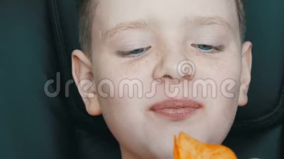坐在大皮椅上吃薯片的蓝眼睛雀斑少年视频的预览图
